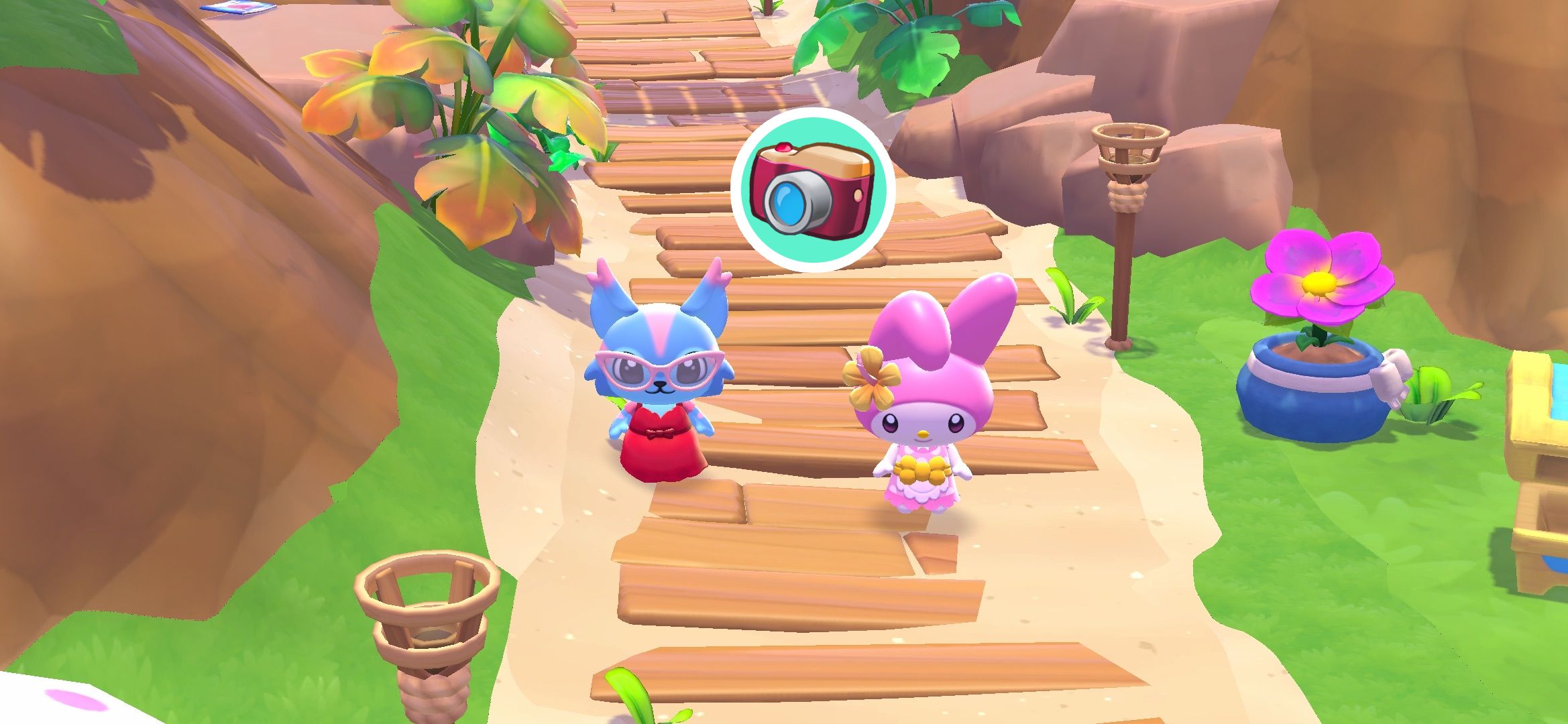 Hello Kitty Island Adventure avatar standing next to My Melody along a wooden beach path. A picture of the game camera is in a teal circle with a white border in the middle above their heads to represent the 'Picture Day' quest.